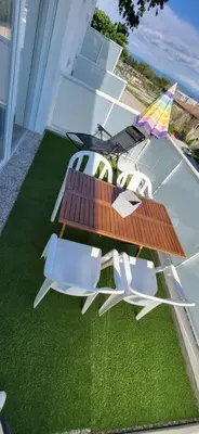 a patio with two chairs and a table on the grass at Appartement avec balcon/terrasse in Monteux