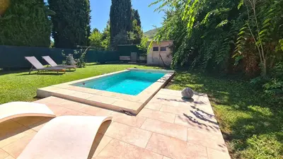 a small swimming pool in a yard with two chairs at Jolie villa loc-saisonnière - la petite cocagne in Alleins