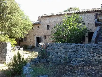 an old stone building with a stone wall at Le Jas des aiguiers in Saint-Saturnin-les-Apt