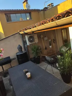 a patio with a table and chairs and a building at Appartement duplex toit terrasse in Apt