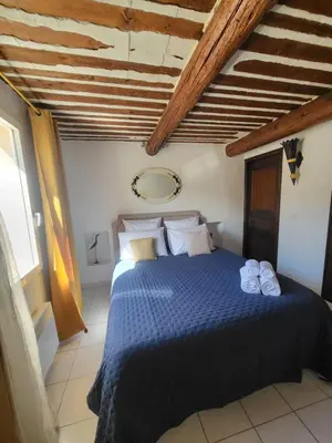 a bedroom with a blue bed with towels on it at Appartement au Cœur de la Sorgue in LʼIsle-sur-la-Sorgue