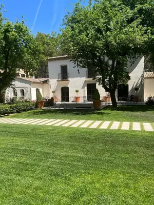 a white house with a tree in the yard at La Bastide des Rosiers in Mallemort