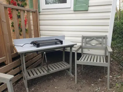 a picnic table and a bench next to a house at Camping Domaine des Iscles in La Roque-dʼAnthéron