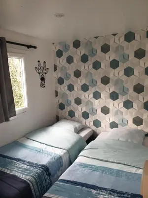 a bedroom with two beds and a geometric wall at Camping Domaine des Iscles in La Roque-dʼAnthéron