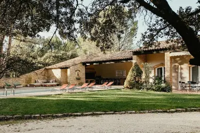 a house with chairs in front of a yard at Villa des Baumes in Cornillon-Confoux