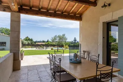 a patio with a table and chairs and a bird cage at Maison style mas « le rougadou » in Noves