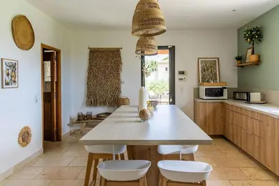 a kitchen with a table with white chairs and a counter at Maison style mas « le rougadou » in Noves