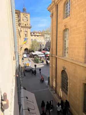 a group of people walking around a street with a clock tower at Studio Mezzanine Mairie in Aix-en-Provence