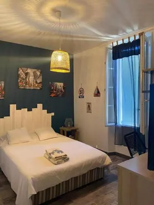 a bedroom with a large bed and a chandelier at Appartement avec jardin en ville in LʼIsle-sur-la-Sorgue
