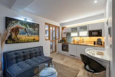 a living room with a blue couch and a kitchen at La Grange de la Chèvre d'Or in Lagnes