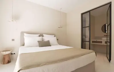 a white bedroom with a large bed with white pillows at Mas La Bergerie in Eygalières