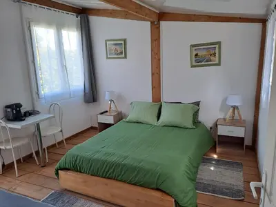 a bedroom with a bed with a green comforter at Chambre basilic 2p, 2 nuits max, dans petit chalet 6km du festival de piano de la roque d'anthéron in Rognes