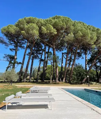 a group of benches next to a pool with trees at La Pavoyère in Mormoiron