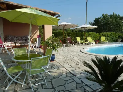 a patio with chairs and an umbrella and a pool at Le Mas du Miel d'Or, 12 pers, au coeur du Luberon, air-conditionné, piscine, propriété de 5000 m2 in Villars