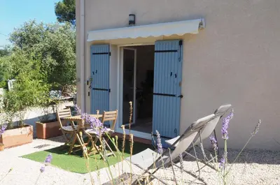 a house with a blue door and two chairs at Paisible studio tout neuf en lisière de forêt in Peyrolles-en-Provence
