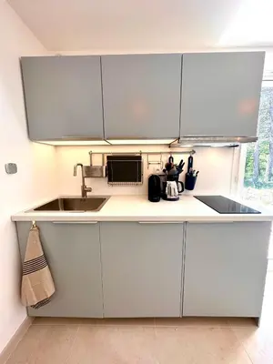a kitchen with white cabinets and a sink at Paisible studio tout neuf en lisière de forêt in Peyrolles-en-Provence