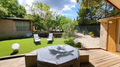 a backyard with a lawn with two chairs and a table at La Tissonnière Oasis d Exception entre Mer Alpilles et Luberon Spa et Piscine à 10 min d Aix en Provence in Saint-Estève-Janson