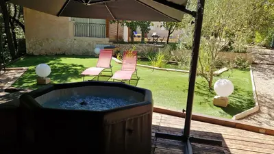 a hot tub in a yard with chairs and an umbrella at La Tissonnière Oasis d Exception entre Mer Alpilles et Luberon Spa et Piscine à 10 min d Aix en Provence in Saint-Estève-Janson