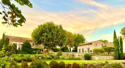 a house in a yard with a stone wall and trees at La Grande Verrière - Luberon en Provence in Goult
