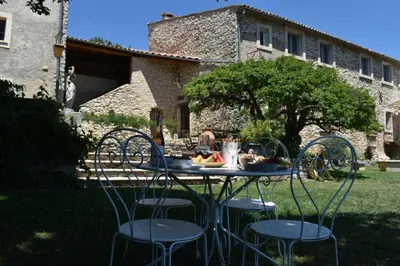 a table with chairs and fruit on it in a yard at Le Domaine de Piedmoure, Gîtes et chambres, piscine, terrasses privatives in Sault-de-Vaucluse