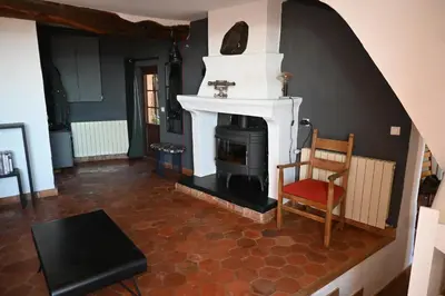 a living room with a fireplace and a chair at Maison Porte Heureuse in Roussillon
