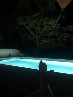 a person laying in front of a swimming pool at night at Le Jas Gabriel in Murs