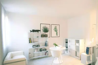 a white living room with a white chair and a table at Joli appartement au cœur de la ville in LʼIsle-sur-la-Sorgue