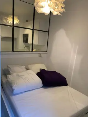 a bed in a room with a mirror on the wall at Joli appartement au cœur de la ville in LʼIsle-sur-la-Sorgue