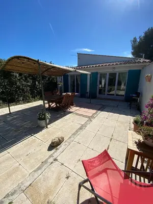 a patio with a red chair and a wooden umbrella at Gîte Lou Gardian in Aureille