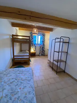 a bedroom with a bed and a chair in a room at Gîte Lou Gardian in Aureille