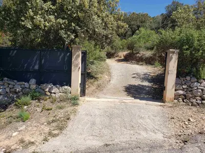 a gate on a dirt road next to a fence at Charmante petite maison de campagne in Jouques