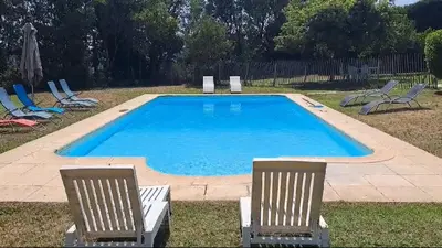 a swimming pool with two lawn chairs and a group of chairs at Magnifique Villa avec piscine in Cadenet