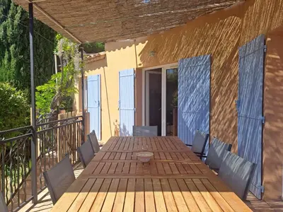 a wooden deck with a table and chairs on a balcony at Magnifique Villa avec piscine in Cadenet