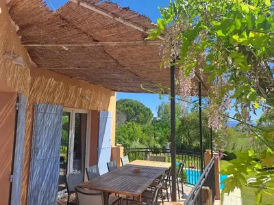 a patio with a wooden table on a deck at Magnifique Villa avec piscine in Cadenet