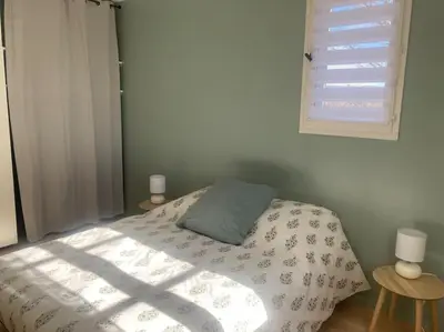 a bedroom with a bed with a blanket and a window at Maison familiale au pied du Mont Ventoux in Mazan