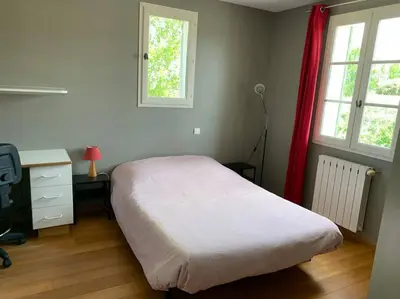 a bedroom with a bed and a desk and windows at Maison familiale au pied du Mont Ventoux in Mazan