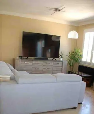 a living room with a white couch and a flat screen tv at La villa castellas in Carpentras