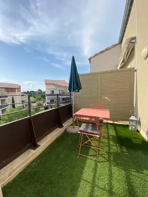 a patio with a red table and an umbrella at Charmant appartement ensoleillé-Terrasse - PARKING Gratuit - Isle sur la Sorgue in LʼIsle-sur-la-Sorgue
