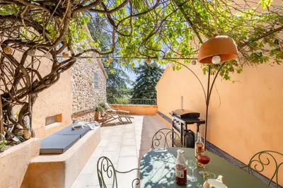 an outdoor patio with a table and a grill at Chez Fanny in Bédoin