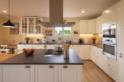 a kitchen with white cabinets and a black counter top at L'Oliveraie in Saint-Saturnin-les-Apt