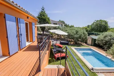 a house with a deck and a swimming pool at L'Oliveraie in Saint-Saturnin-les-Apt