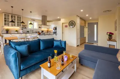 a living room with two blue couches and a kitchen at L'Oliveraie in Saint-Saturnin-les-Apt