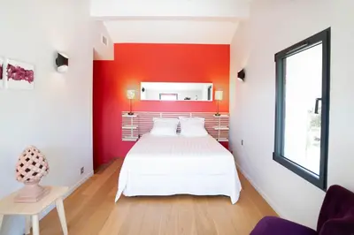 a bedroom with a white bed and a red wall at Villa climatisée avec vue en pleine pinède aixoise in Saint-Marc-Jaumegarde