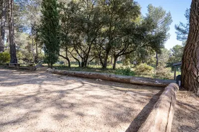 a wooden fence in a park with trees at Villa climatisée avec vue en pleine pinède aixoise in Saint-Marc-Jaumegarde
