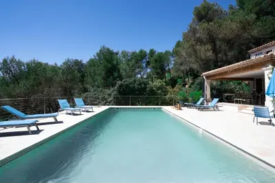 a swimming pool with blue lounge chairs and a swimming pool at Villa climatisée avec vue en pleine pinède aixoise in Saint-Marc-Jaumegarde