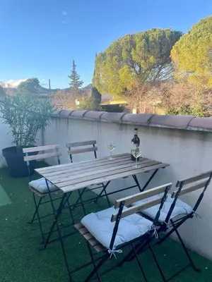 a wooden table with two chairs and a bottle of wine at Le Lourmarinois in Lourmarin