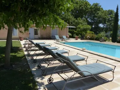 a row of lounge chairs next to a swimming pool at Luberon - Mas du Grand Saint Julien in Rustrel