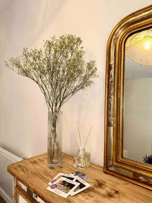 a vase of flowers on a table next to a mirror at Lou Paseo : Appartement Brocante centre historique in LʼIsle-sur-la-Sorgue