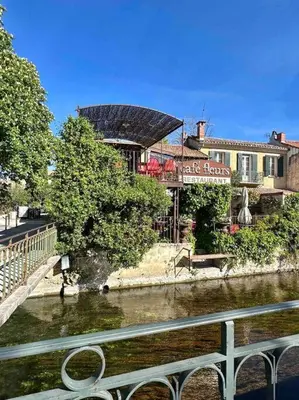 a bridge over a river in front of a building at Lou Paseo : Appartement Brocante centre historique in LʼIsle-sur-la-Sorgue