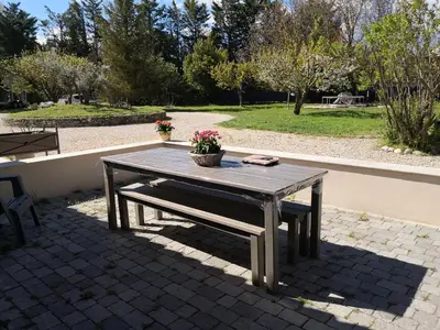 a picnic table with a bench and flowers on it at Mas Paolo Gite de charme en Provence Piscine in Le Thor